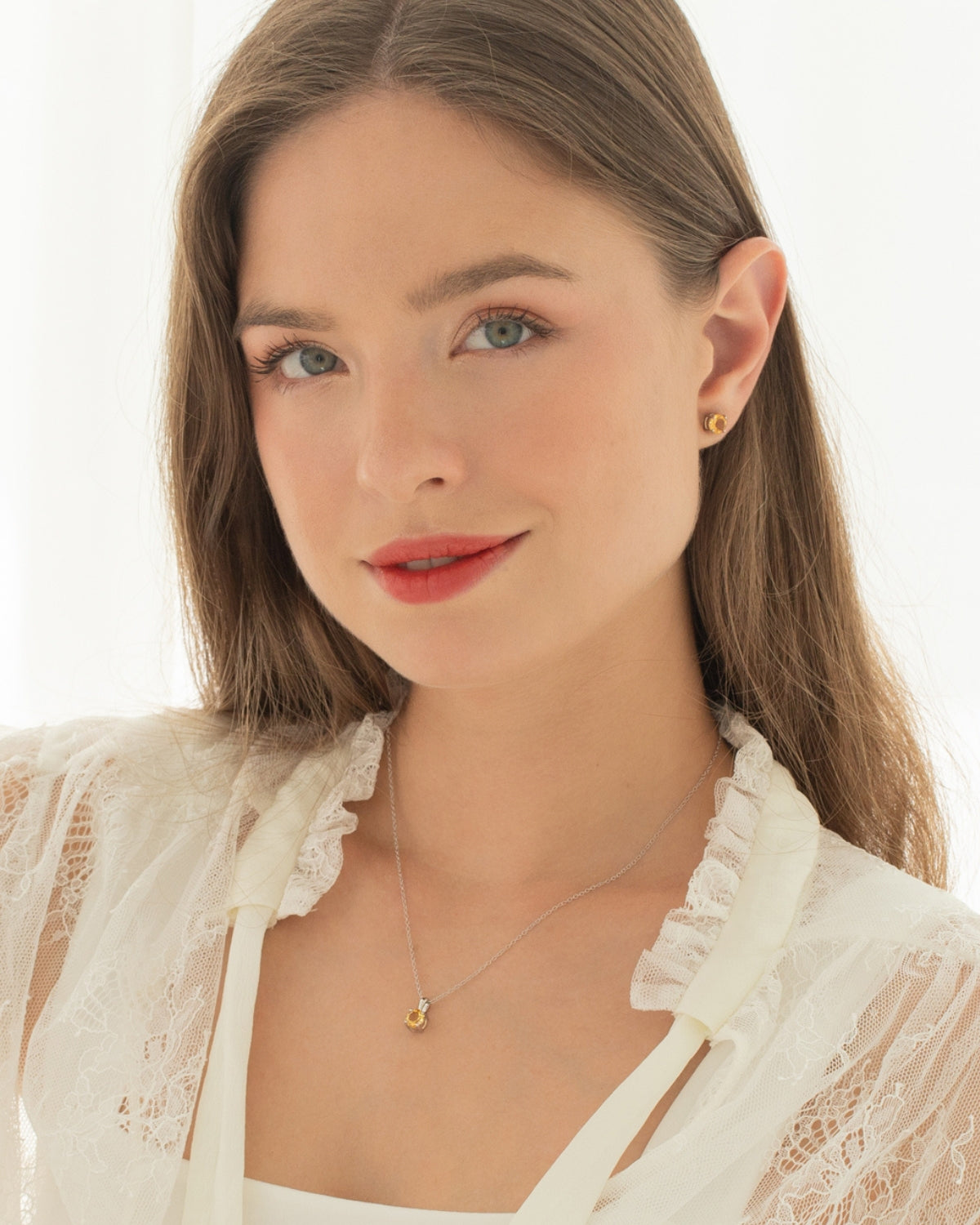 Woman wearing a citrine necklace and earring set on a light background