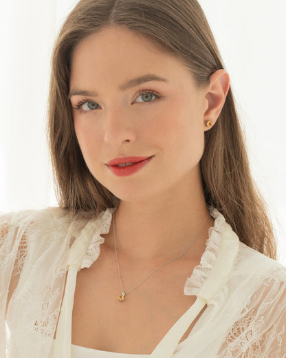 Woman wearing a citrine necklace and earring set on a light background