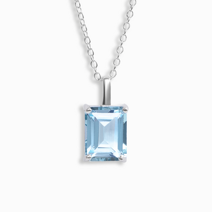 Silver necklace with a blue topaz gemstone pendant on a white background