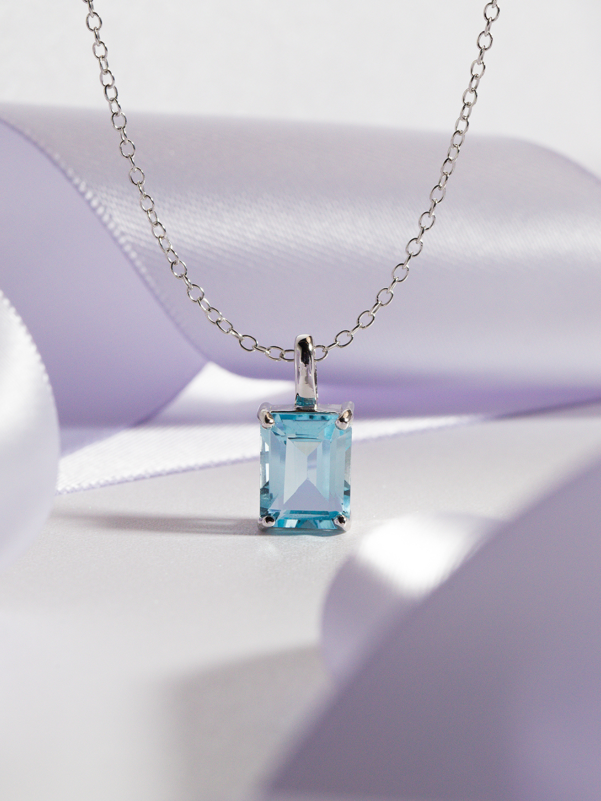 Necklace with a blue topaz gemstone pendant on a purple background