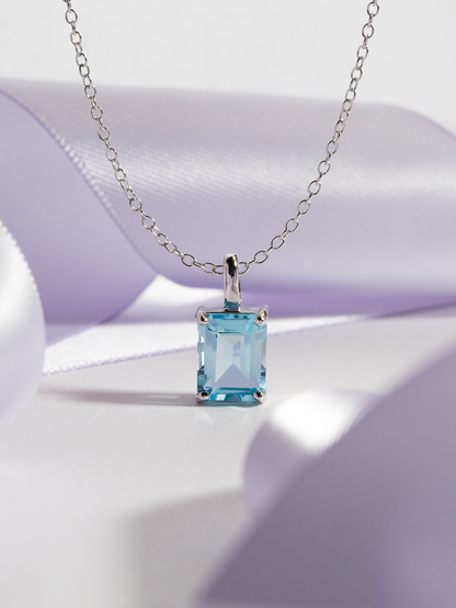 Necklace with a blue topaz gemstone pendant on a purple background