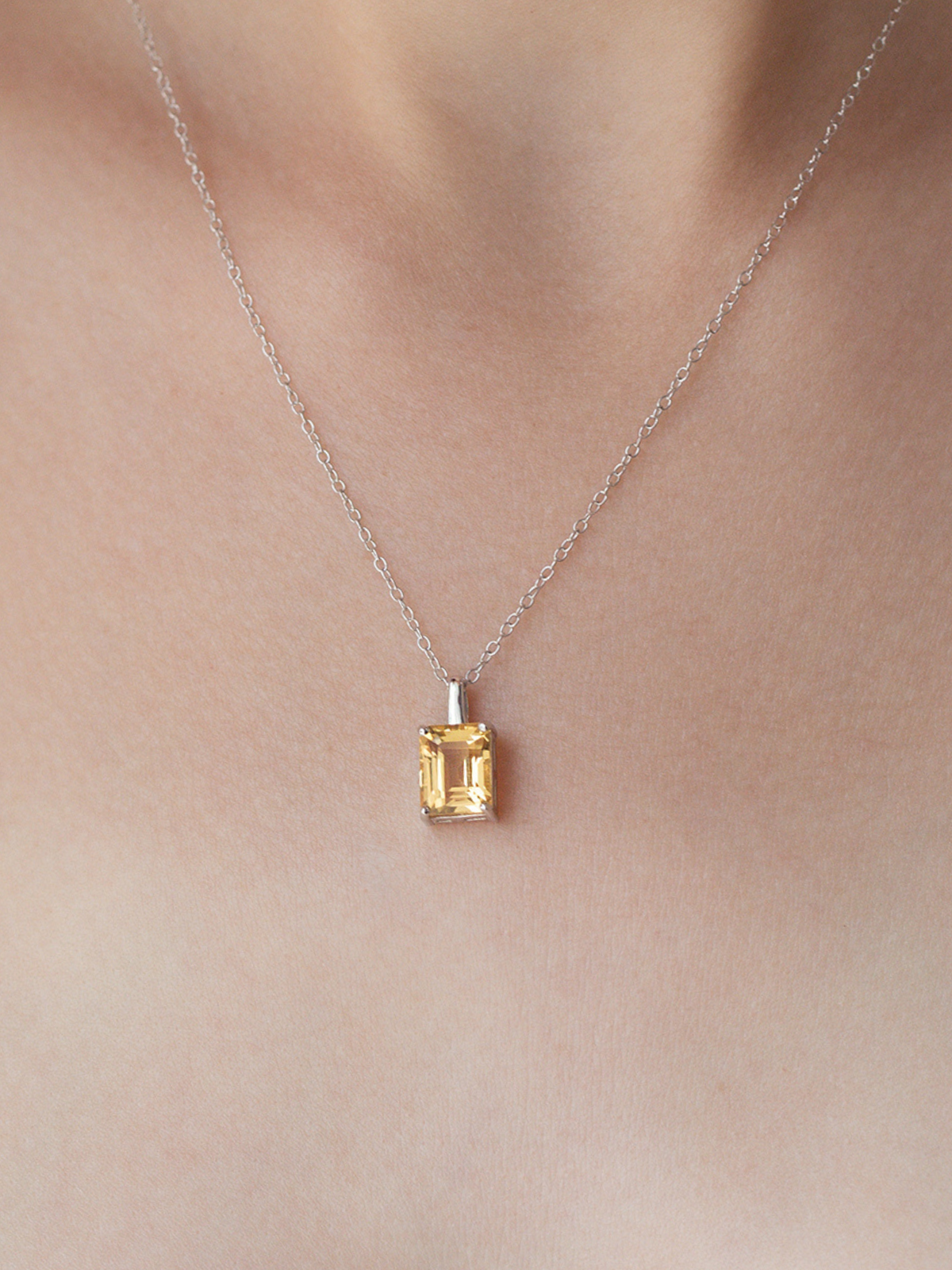 Necklace with a yellow citrine gemstone pendant on a plain background