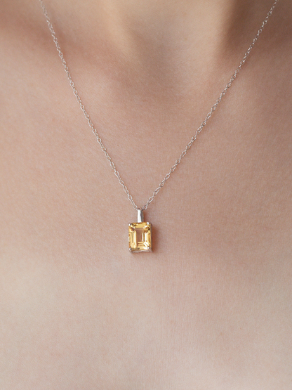 Necklace with a yellow citrine gemstone pendant on a plain background