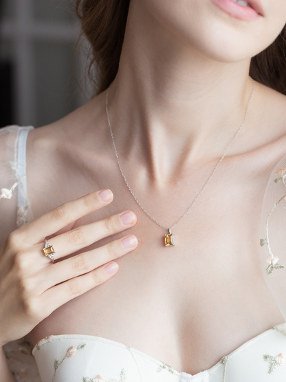 Woman wearing a silver citrine necklace and ring, with a blurred background