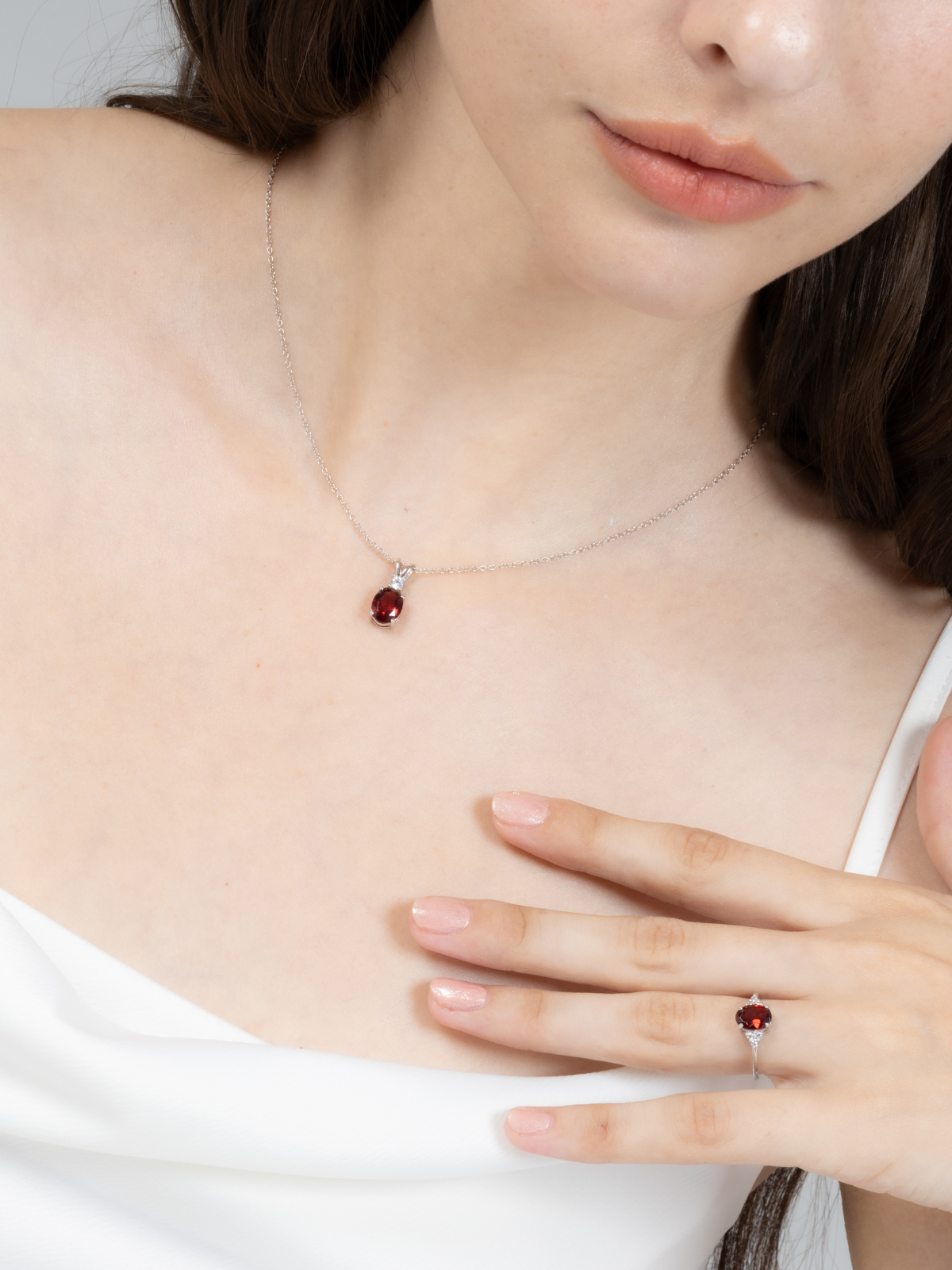 Woman wearing a necklace and ring with a red garnet gemstone