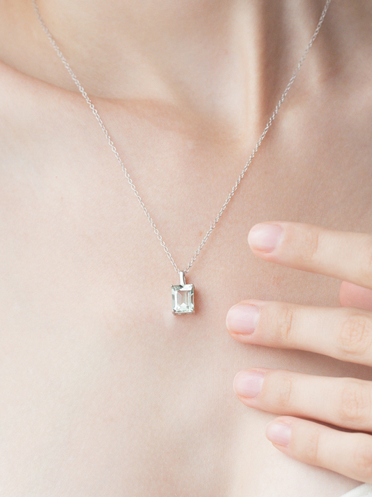 Silver necklace with a rectangular green amethyst pendant on a person's neck