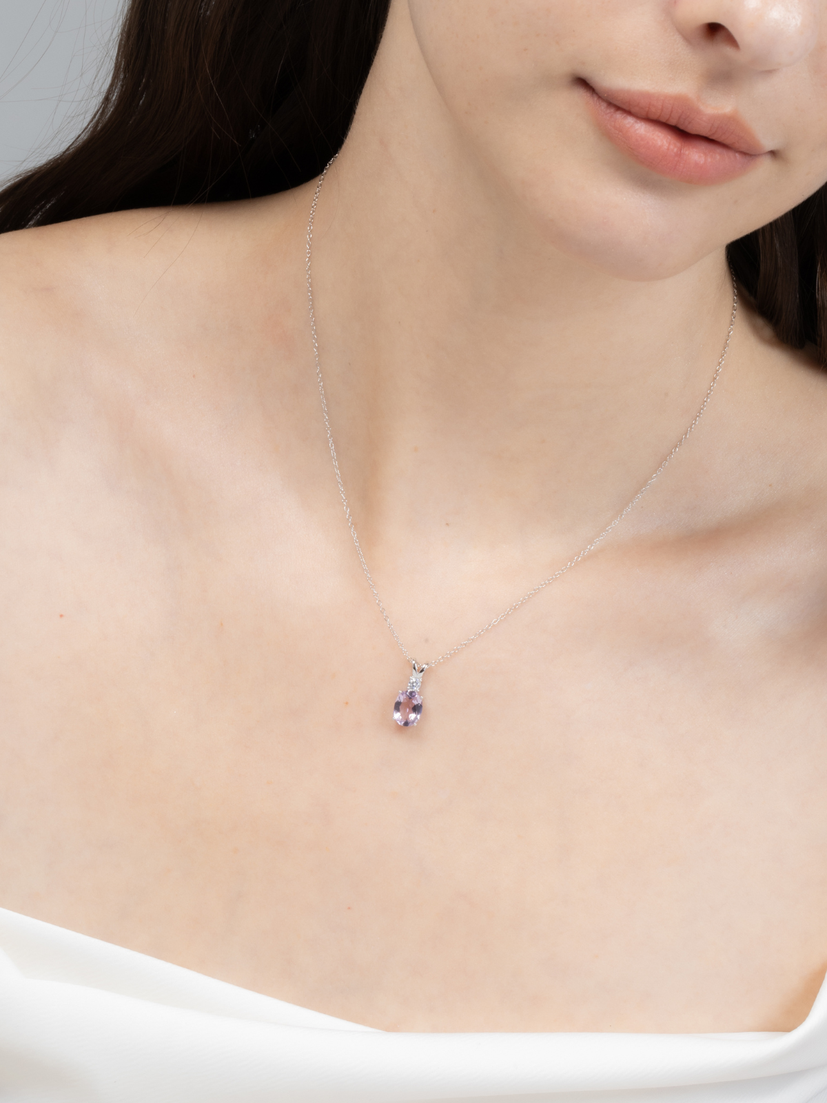 Silver Necklace with an amethyst pendant worn by a person against a neutral background