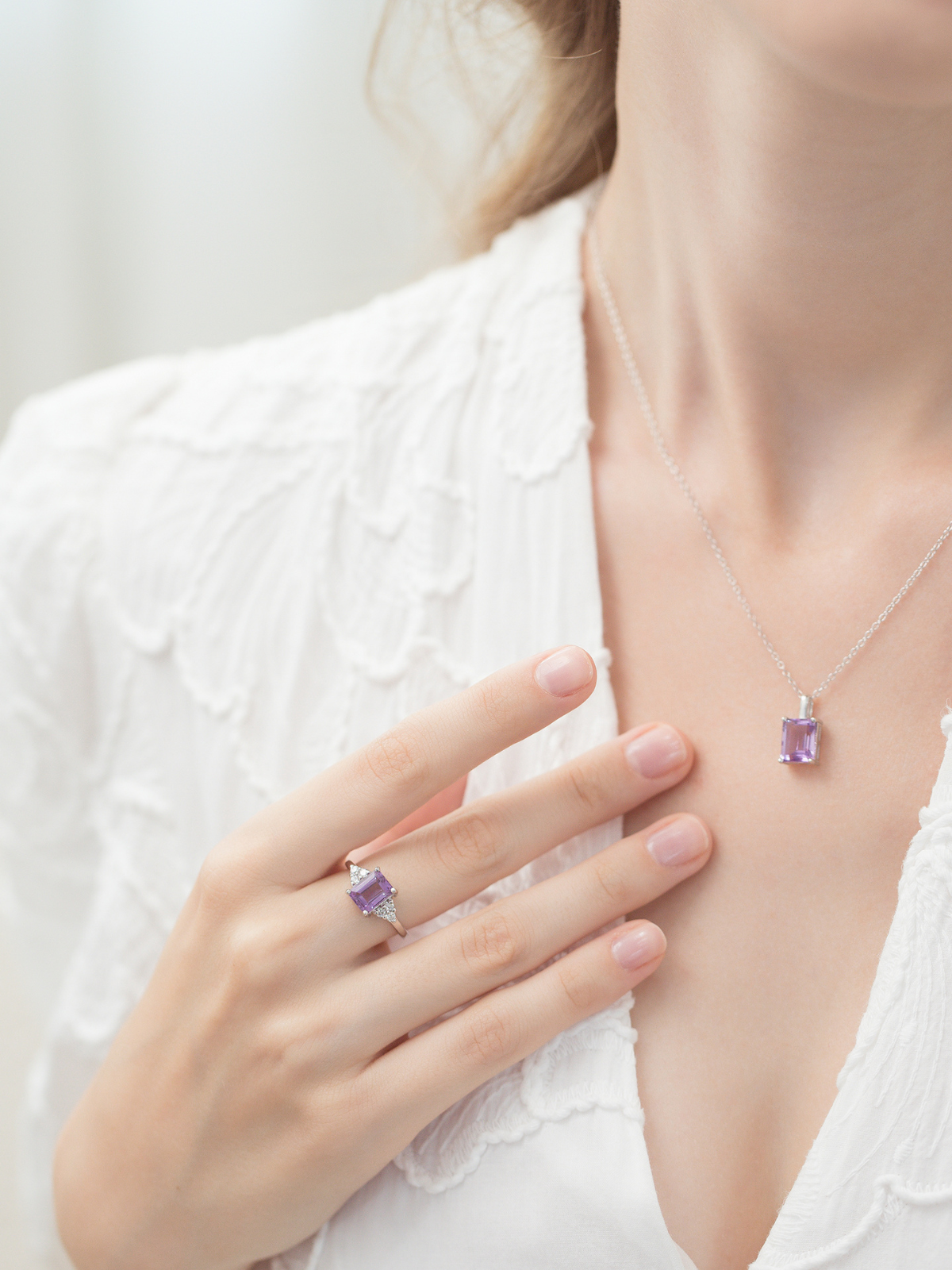 Women wearing a necklace and ring with purple amethyst gemstones on a white background