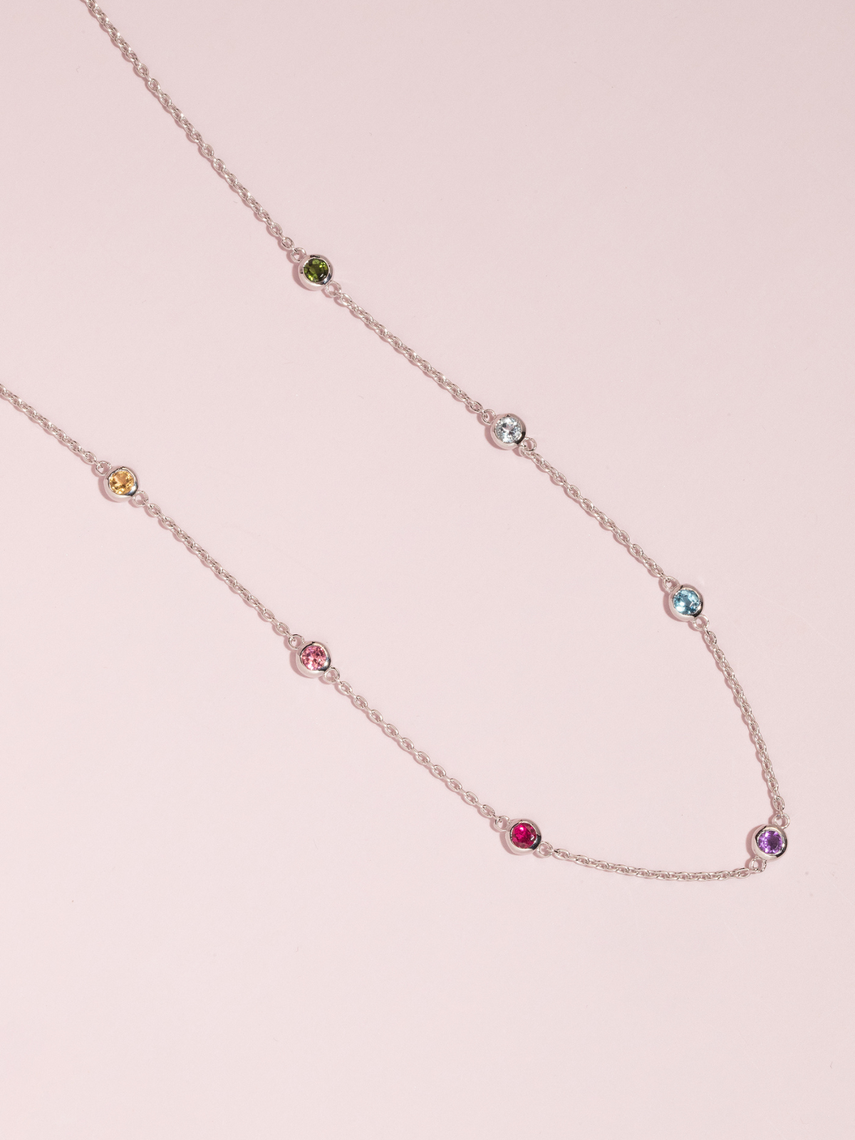 Necklace with multicolored gemstones on a pink background