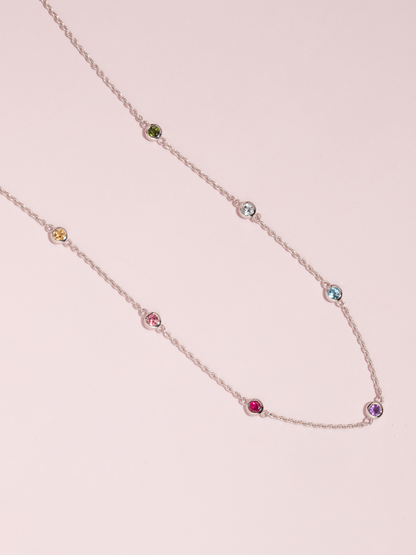 Necklace with multicolored gemstones on a pink background