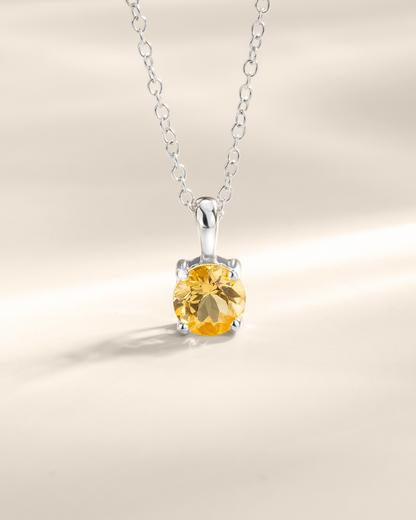 Silver necklace with a yellow citrine gemstone pendant on a neutral background