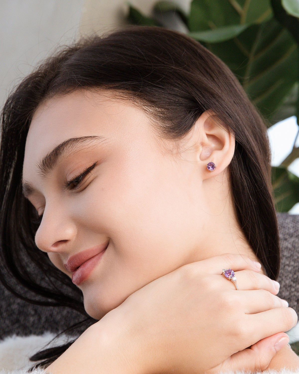 Woman wearing an amethyst ring and earrings with a blurred background