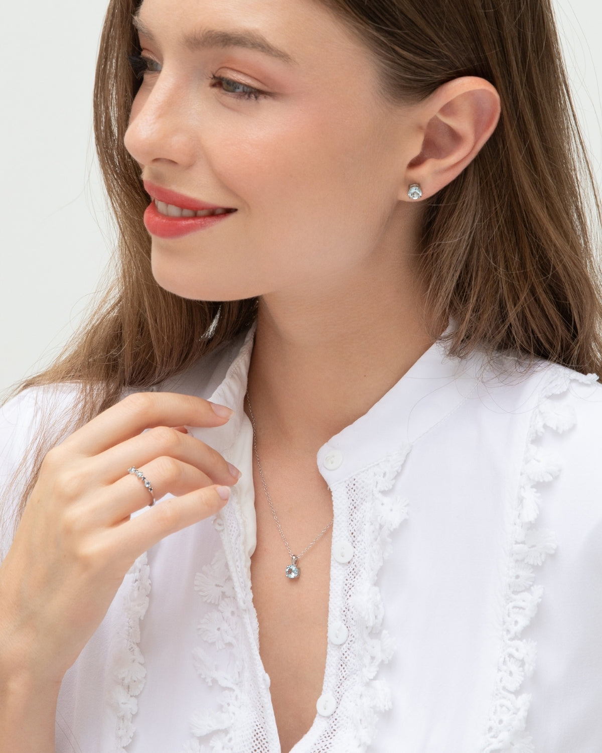 Woman wearing a blue topaz necklace and earrings on a white background