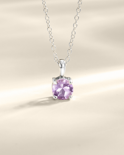 Silver necklace with a purple amethyst gemstone pendant on a beige background