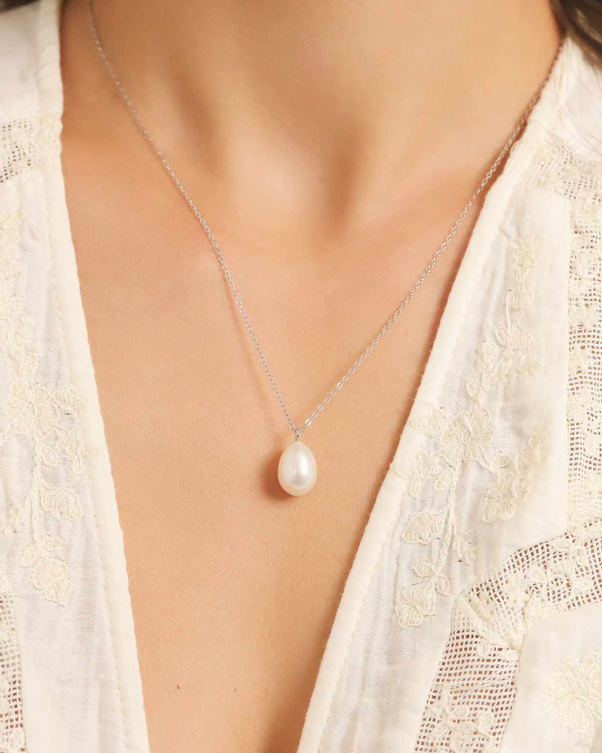 Pearl silver necklace on a woman with a white lace garment