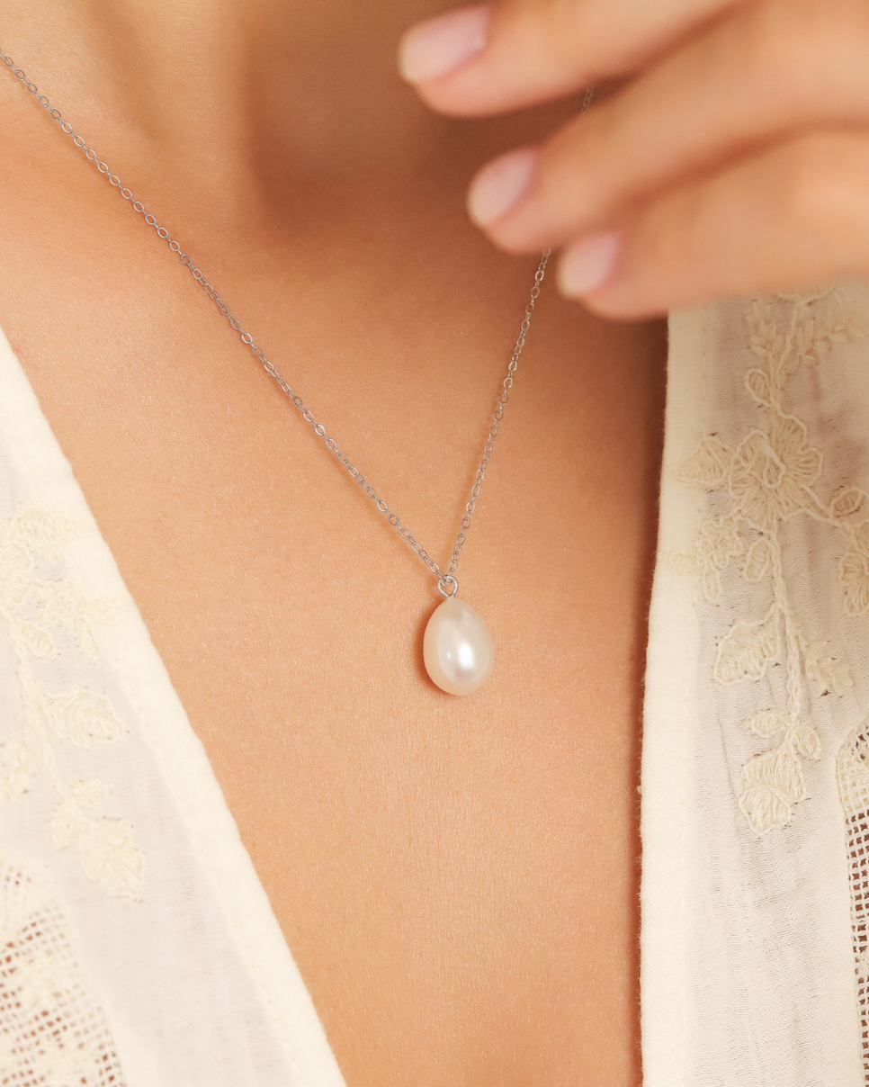 Pearl and silver necklace being worn with a woman