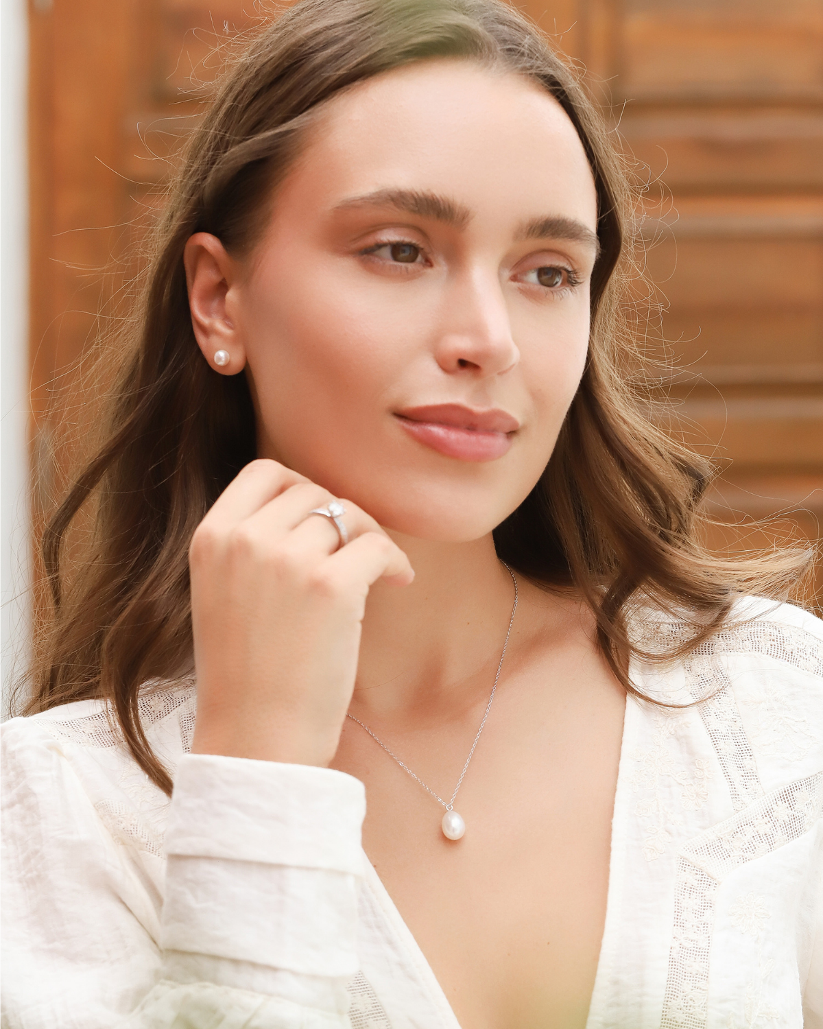 Woman wearing a pearl necklace with a blurred wooden background