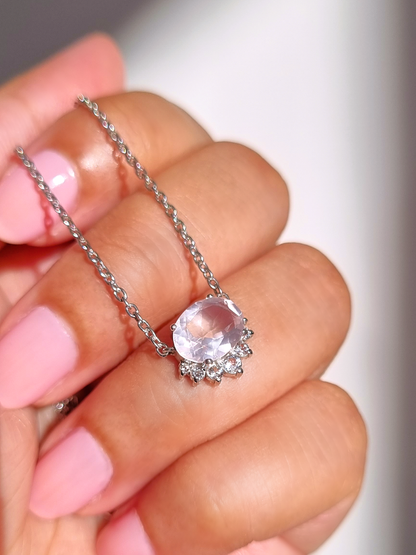 Silver necklace with a rose quartz gemstone held by a hand