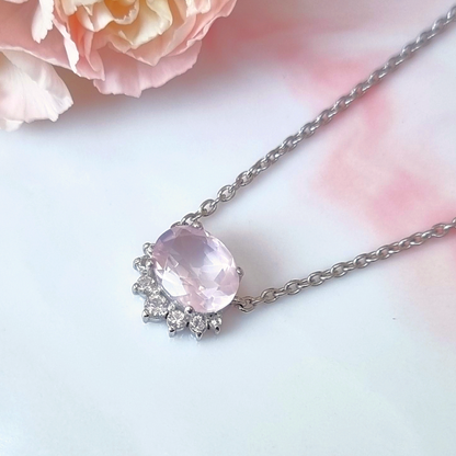 Necklace with a rose quartz gemstone pendant on a soft pink background