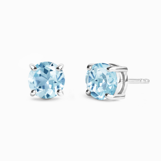 Pair of silver stud earrings with light blue topaz gemstones on a white background