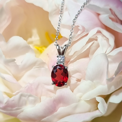 Red garnet gemstone necklace on a white flower background