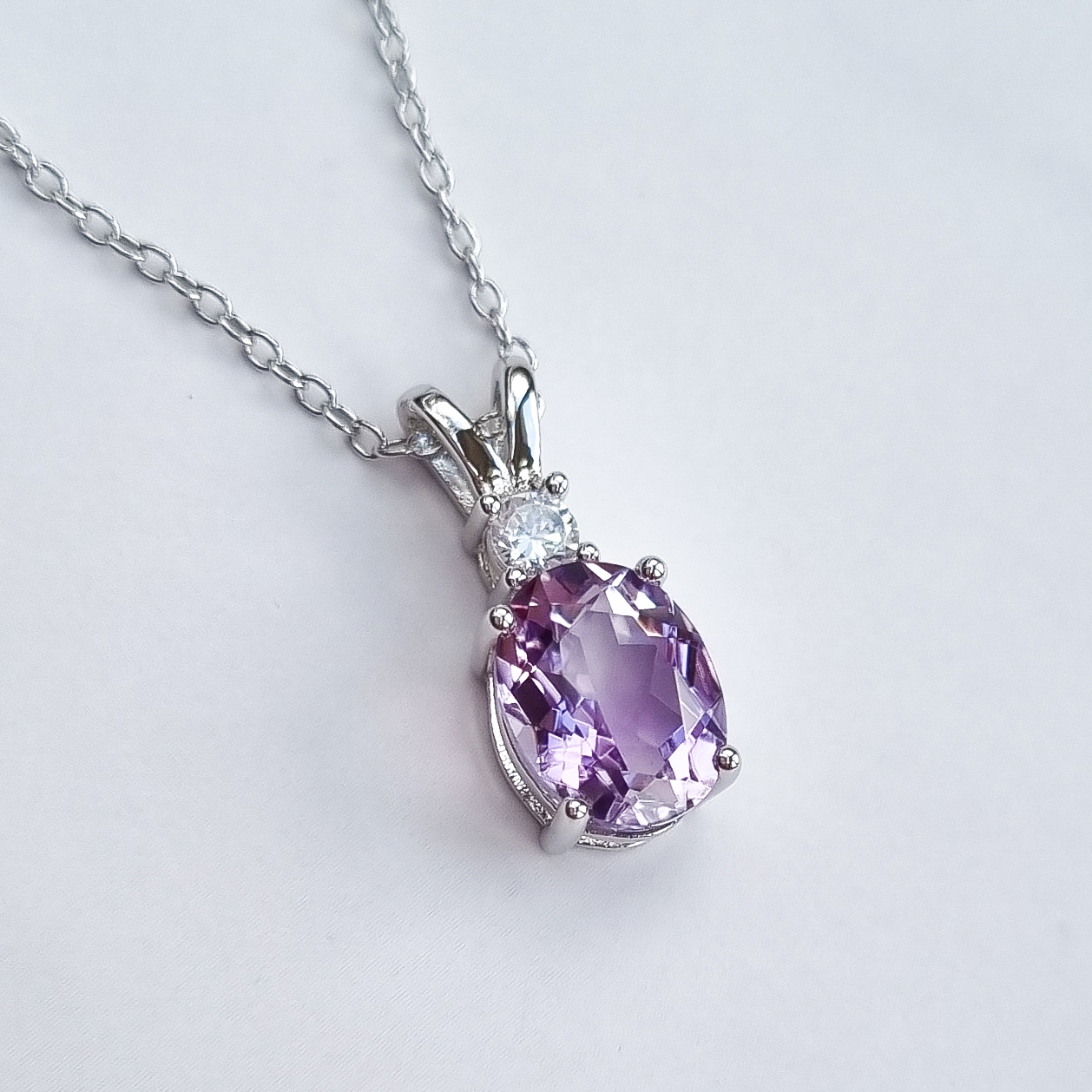 Purple amethyst gemstone silver necklace on a light grey background