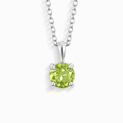 Green peridot gemstone pendant on a silver chain against a white background