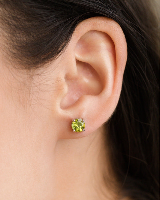 Close-up of an ear wearing a green peridot gemstone stud earring.