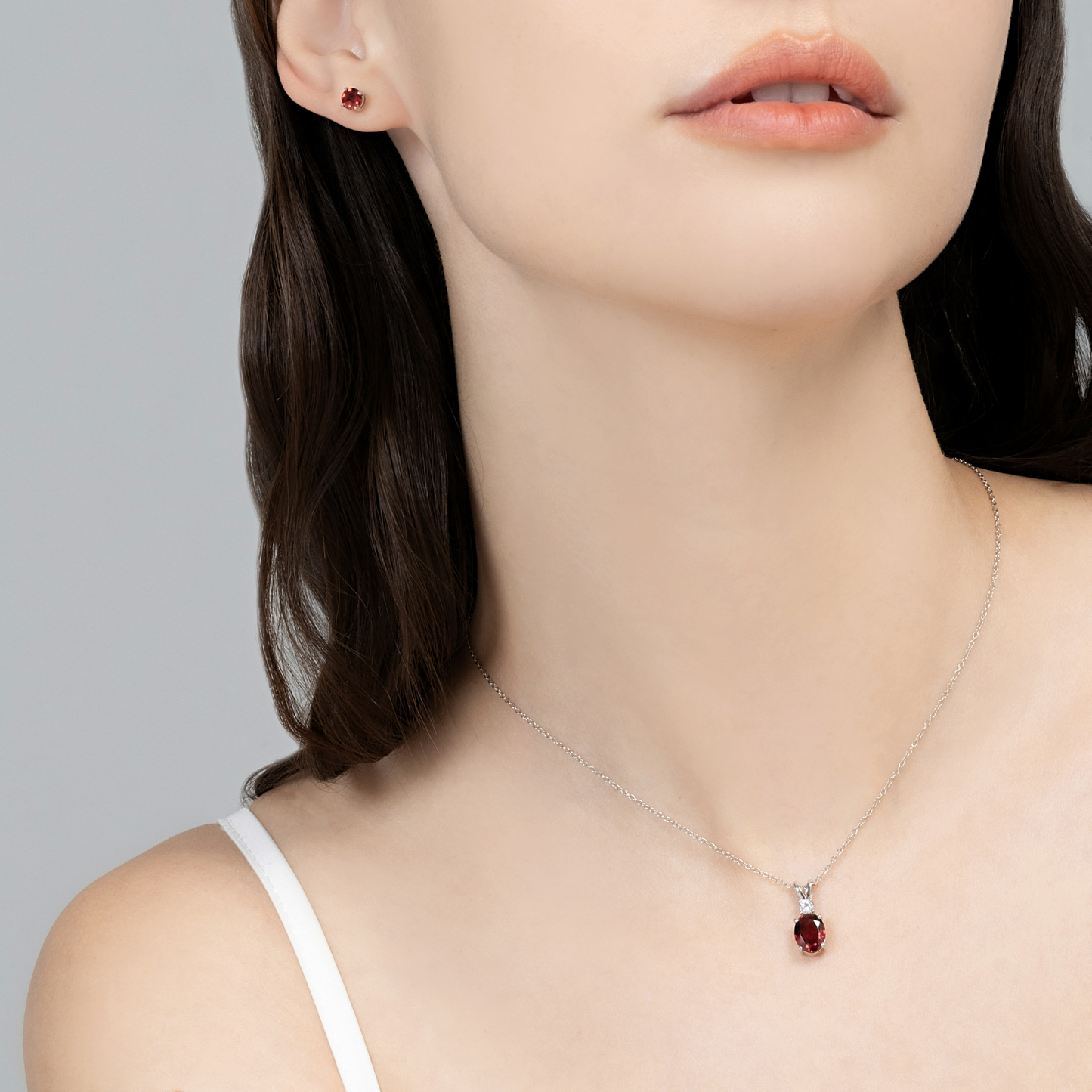 Woman wearing a silver necklace with a red garnet gemstone pendant