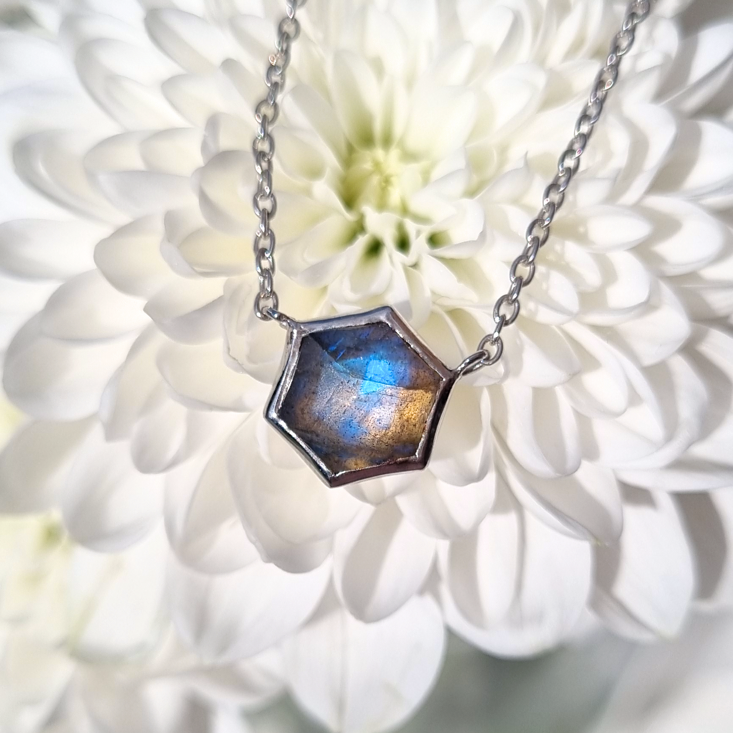 Labradorite Necklace with a hexagonal pendant on a white flower background