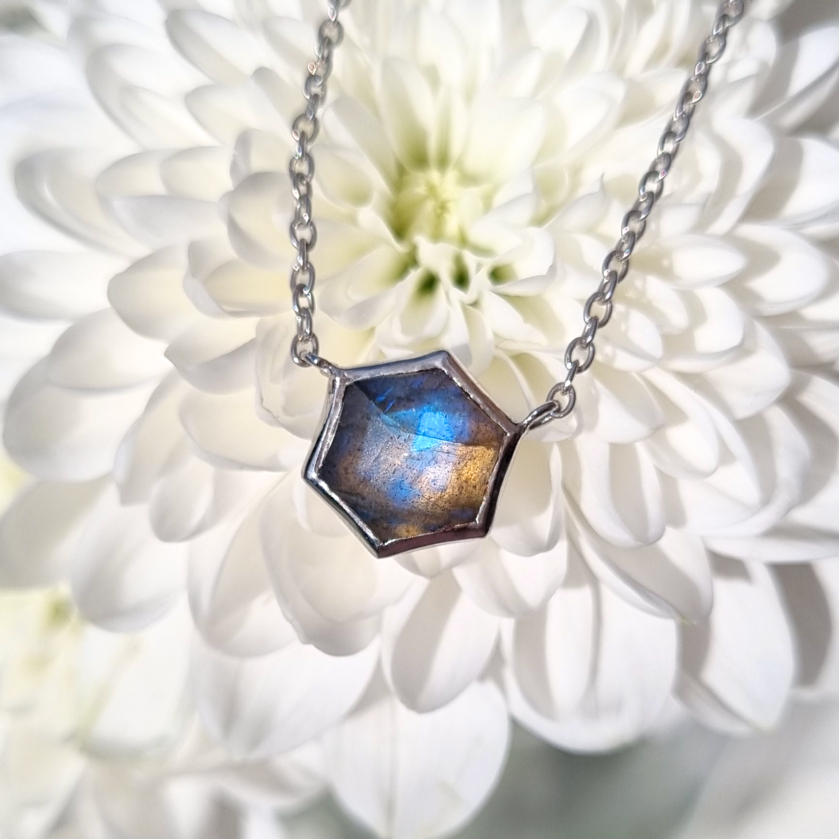 Labradorite Necklace with a hexagonal pendant on a white flower background