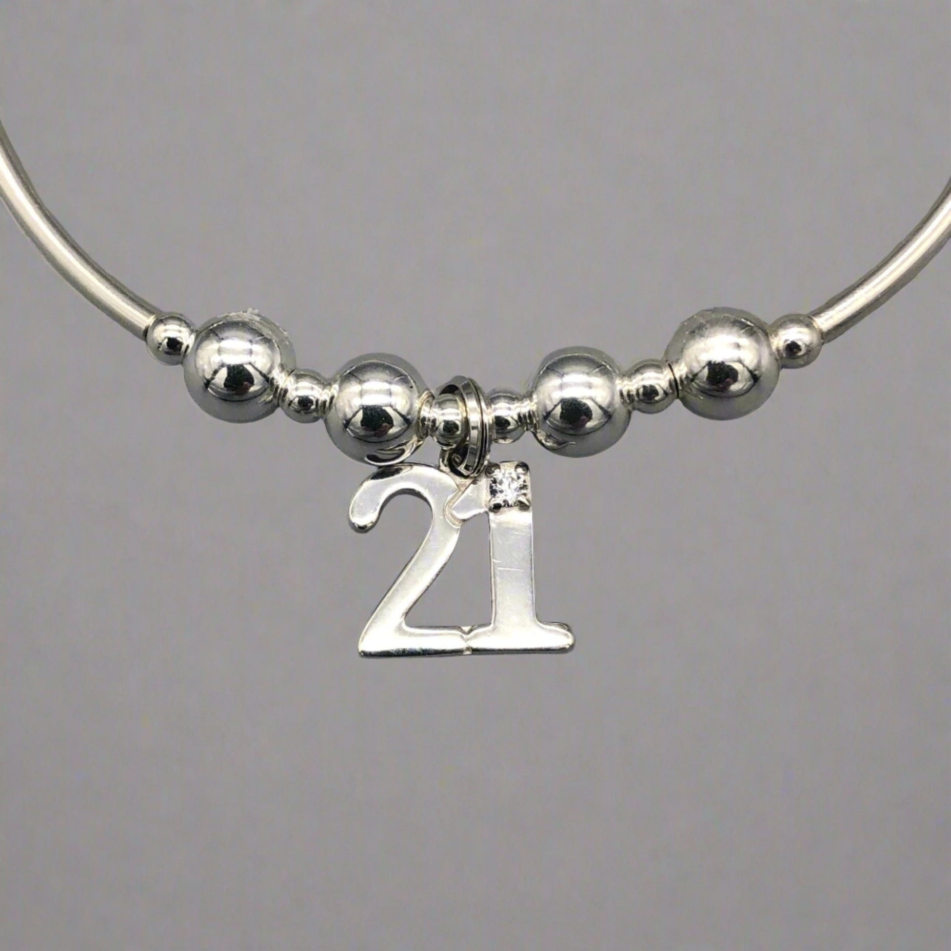Closeup of 21st Birthday charm women's sterling silver stacking bracelet by My Silver Wish