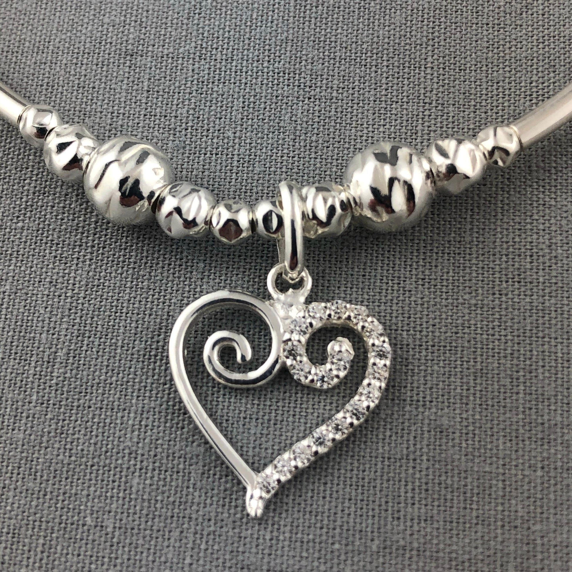 Closeup of Swirl heart charm sterling silver stacking charm bracelet by My Silver Wish