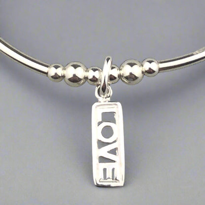 Closeup of "Love" rainbow & sterling silver women's stacking charm bracelet by My Silver Wish