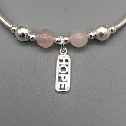 Closeup of "Hope" rose quartz healing crystal women's silver stacking charm bracelet by My Silver Wish